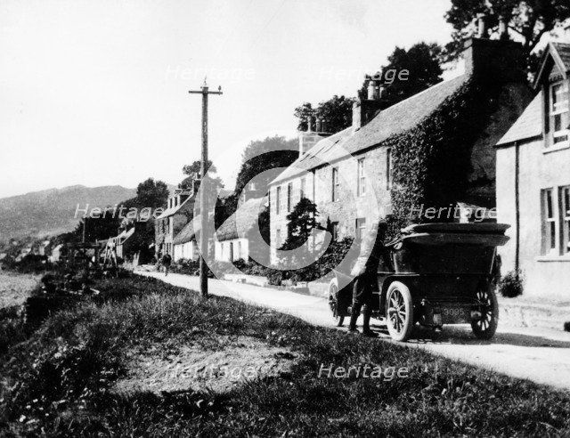 A man by his car in a village lane, 1900. Artist: Unknown