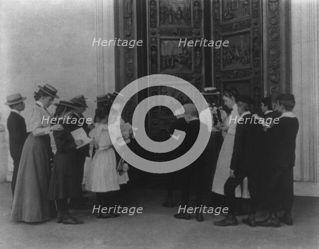 Washington, D.C. school children on field trip - examining the bronze "Columbus" door..., (1899?). Creator: Frances Benjamin Johnston.