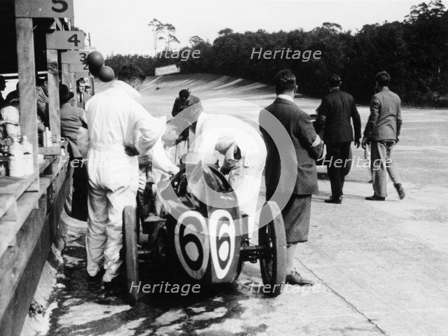 Austin by the pit wall, 500 Mile Race, Brooklands, Surrey, (1931?). Artist: Unknown