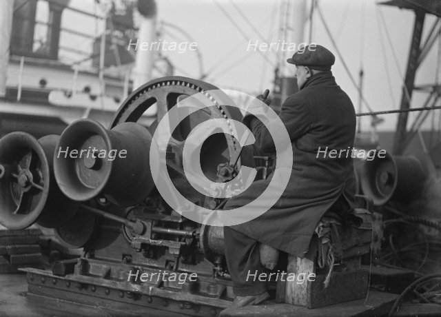 A docker operates a winching gear in London Docks, London, c1945-c1965.  Artist: SW Rawlings