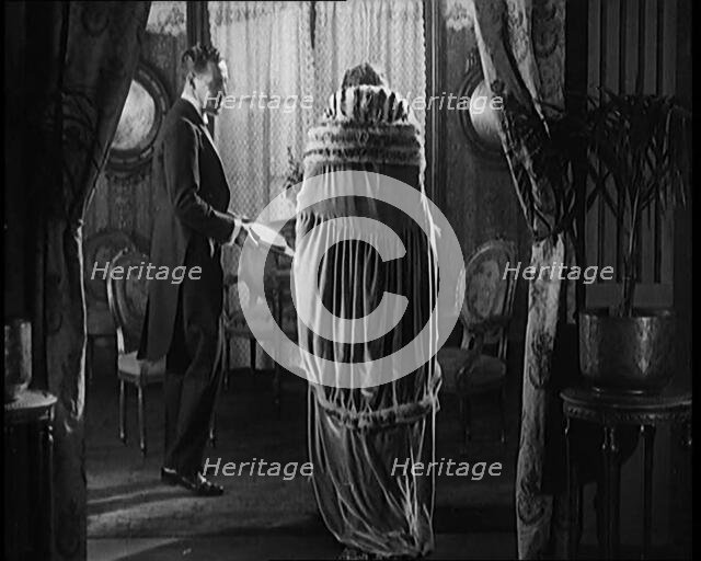 A Civilian Couple Wearing Evening Outfits Entering a Drawing Room, 1920. Creator: British Pathe Ltd.
