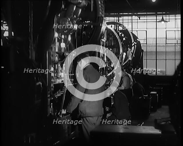 Male Civilians Working Large Presses in a Factory, 1931. Creator: British Pathe Ltd.