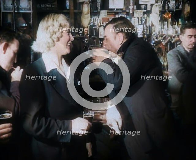 A British Woman and a British Man Standing at  the Bar Holding Drinks in a Public House..., 1939. Creator: British Pathe Ltd.