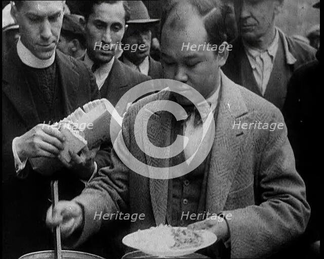 Man Serving Meals For Group of People from the Street Kitchen, 1932. Creator: British Pathe Ltd.