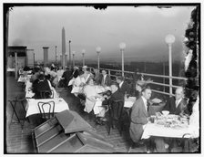 Dining on rooftop; Washington monument in background, between 1910 and 1920. Creator: Harris & Ewing.