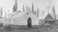 Tent next to log cabin, between c1900 and 1916. Creator: Unknown.