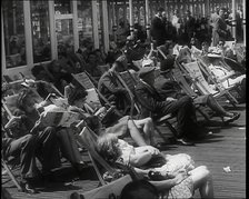 Lines of Men and Women Sitting in Deckchairs on a Pier at  Brighton With Several Reading..., 1939. Creator: British Pathe Ltd.