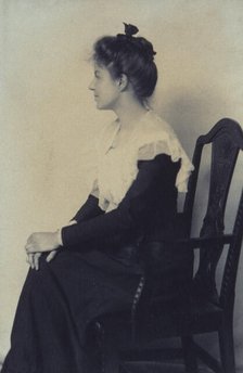 Profile portrait of a woman seated in chair, facing left with hands on her knees, c1900. Creator: Misses Selby.