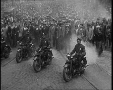 Male American Police Officers Riding Motorbikes Escorting a Large Crowd in a Parade, 1930. Creator: British Pathe Ltd.