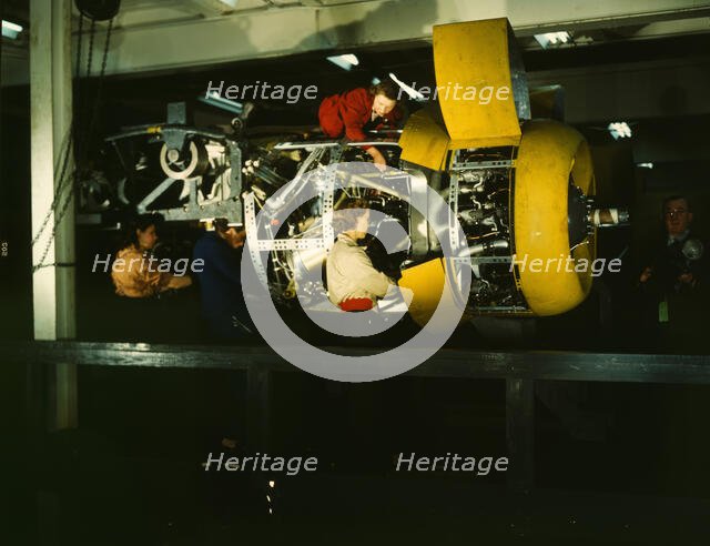 Installing one of the 4 motors on the transport plane at Willow Run, between 1941 and 1945. Creator: Howard Hollem.
