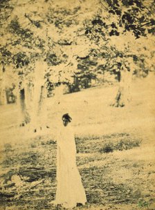 Woman standing in a park, trees in background, c1900. Creator: Eva Watson-Schutze.