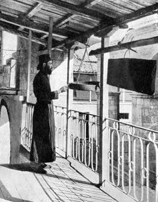 Monk sounding the call to prayer on a gong, Greece, 1936.Artist: Nomias