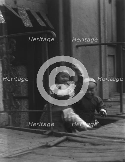 Three children in front of a cellar door, Chinatown, San Francisco, between 1896 and 1906. Creator: Arnold Genthe.