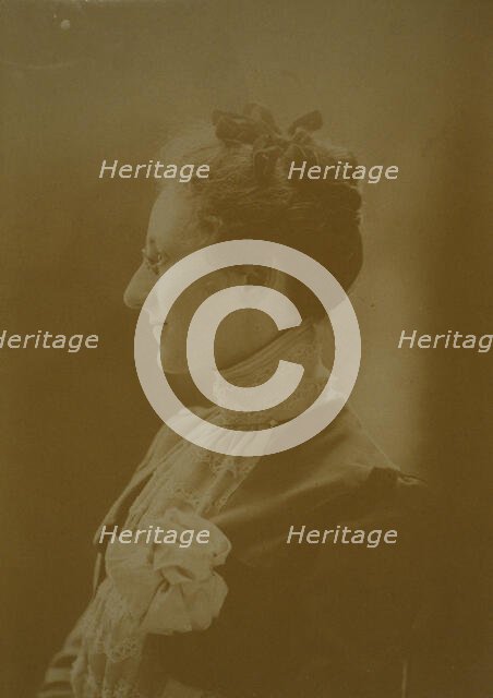 Studio portrait of young woman in white dress posed as if holding flowering tree branch, c1900. Creator: Unknown.
