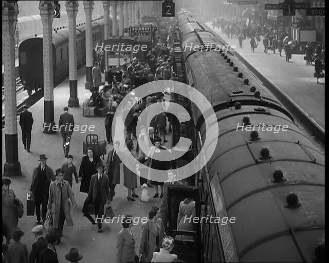 Looking Down Along a Train Platform With Passengers Walking Along, Embarking and Disembark..., 1938. Creator: British Pathe Ltd.