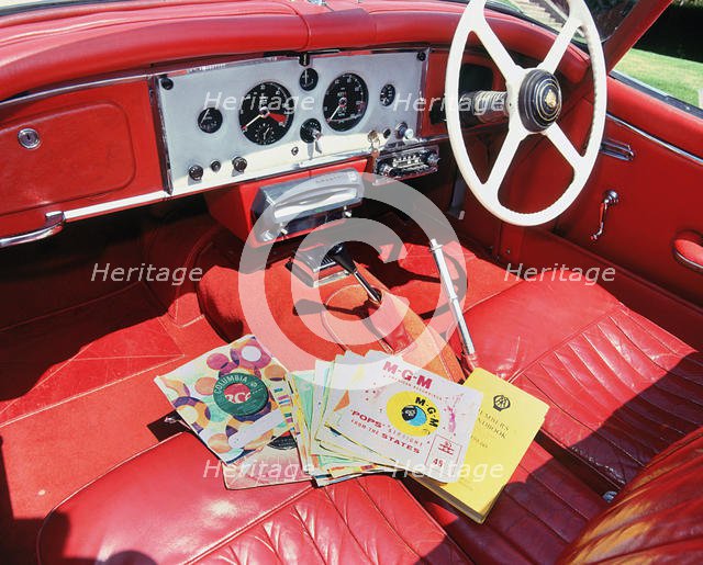 1960 Jaguar XK150 interior with record player and 7inch vinyl discs.. Creator: Unknown.