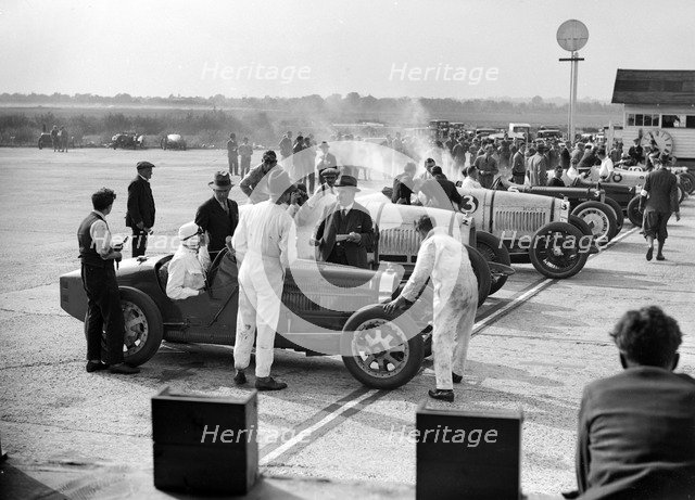 Cars on the start line, Surbiton Motor Club race meeting, Brooklands, Surrey, 1928. Artist: Bill Brunell.