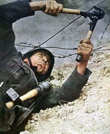 A German soldier cutting through barbed wire during an assalt, 1942. Artist: Unknown