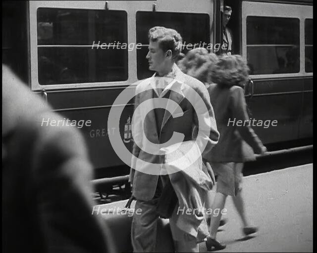 A Man in a Casual Suit and Carrying a Coat and Suitcase Walking Along a Platform Having..., 1938. Creator: British Pathe Ltd.