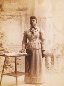 Studio portrait of woman, hand on books spread on table, (1880-1940?). Creator: Madison Art Studio.