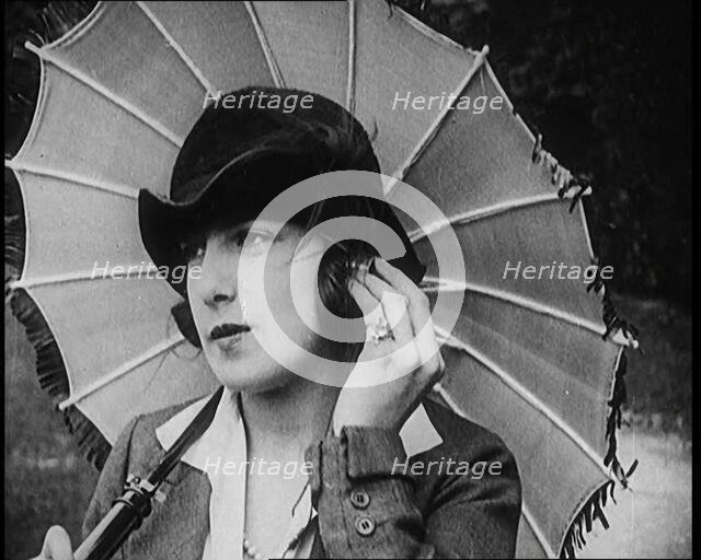 Fashionable Lady Sitting in a Garden Wearing Headphones and Carrying a Parasol, 1922. Creator: British Pathe Ltd.