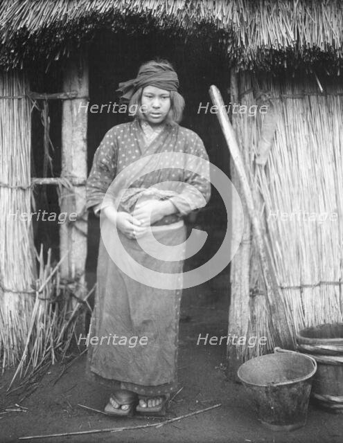 Ainu woman standing by the doorway of a hut, 1908. Creator: Arnold Genthe.