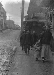 Man and a boy walking down a sidewalk with other people, Chinatown, San Francisco, c1896-1906. Creator: Arnold Genthe.