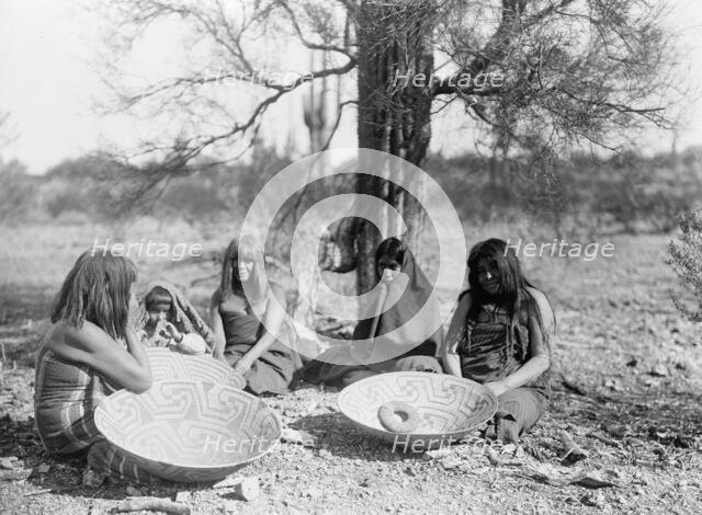 Maricopa group, Arizona. Four women and a child seated on ground with three large basket trays,c1907 Creator: Edward Sheriff Curtis.