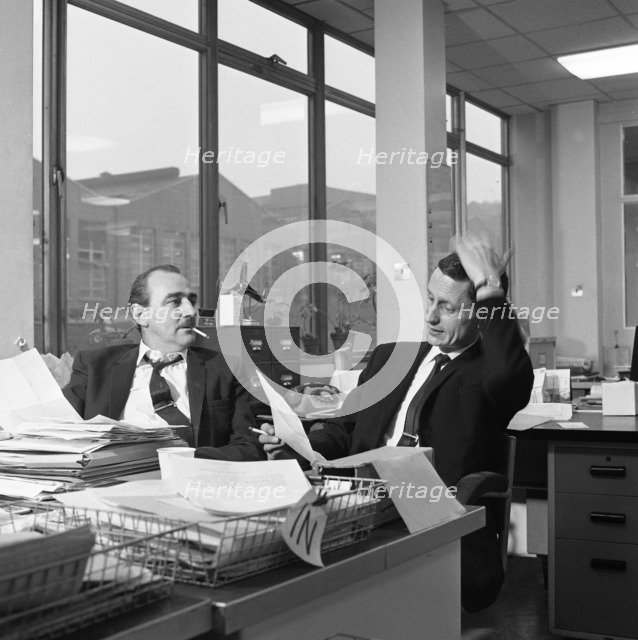 Lost order? two salesmen try to sort out the orders over a cigarette, 1967. Artist: Michael Walters