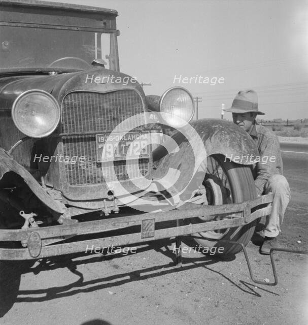 Migrant worker from Oklahoma repairing tire on California highway, 1936. Creator: Dorothea Lange.