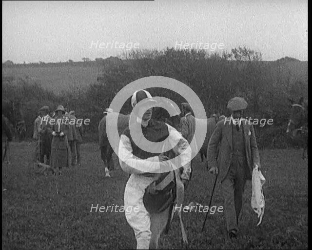 A Female Civilian Wearing a Jockey's Outfit Walking on a Horse Racing Track Watched by a..., 1920. Creator: British Pathe Ltd.
