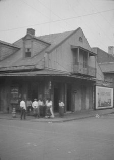 View from across street of a group of men on a street corner, New Orleans, between 1920 and 1926. Creator: Arnold Genthe.