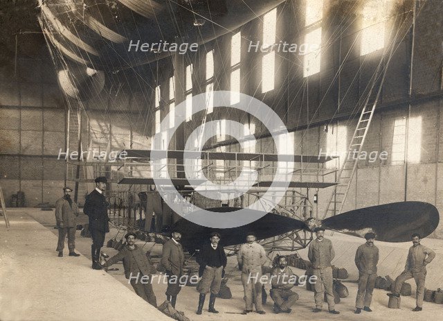 France. Hangar with the cockpit of an airship and a group of mechanics and pilots, 1900s.