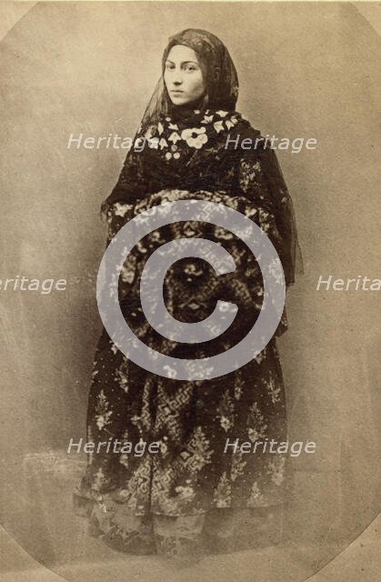 Full-length portrait of a woman in traditional dress, facing slightly left, between 1870 and 1886. Creator: Unknown.