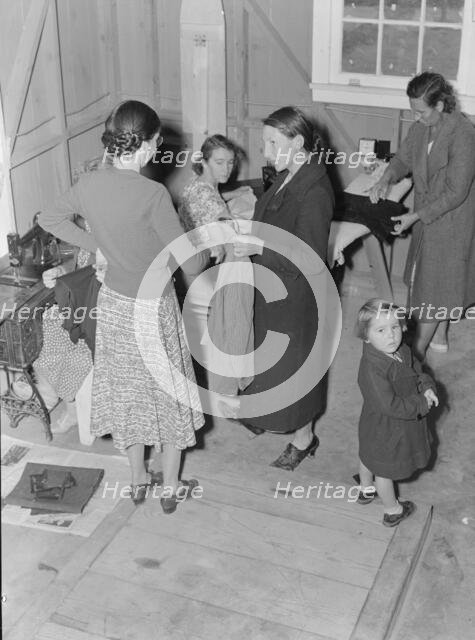 Camper receives help in fitting a coat from WPA sewing instructor, FSA, California, 1938. Creator: Dorothea Lange.