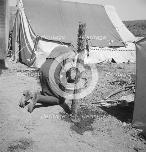A grandmother washing clothes in California, in a contractor's camp near Westley, California, 1939. Creator: Dorothea Lange.