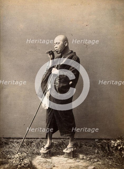 A blind Japanese masseur with a pipe in his mouth and a long pole in his hand, c1890s. Creator: Unknown.
