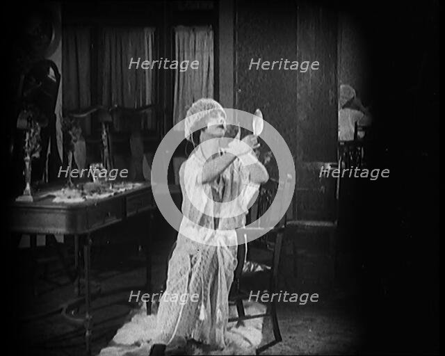 Female Civilian Seating in Front of a Dressing Table Wearing a Nightgown and Boudoir Cap..., 1920. Creator: British Pathe Ltd.
