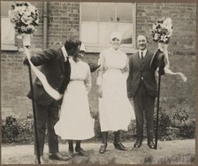 Two men holding tutti poles, with two women during the Hocktide Festival in Hungerford, 1925-35.  Creator: George R Long.