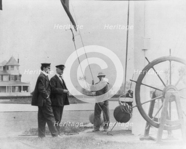 New York Yacht Club, Oyster Bay, L.I., 1905: 2 men watching sailor hoist flag, 1905. Creator: Frances Benjamin Johnston.