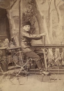 A boy on a bicycle in a photo studio, 1880. Creator: Unknown.