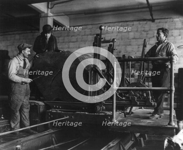Wooden box industry - Mrs. Graham inspecting log on machinery with two workmen standing by, c1910. Creator: Frances Benjamin Johnston.