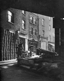 Fruit baskets piled against houses at Borough Market, London, 1926-1927.Artist: Whiffin