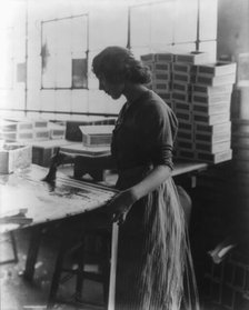 Girl painting strips with glue to assemble cigar boxes, c1910. Creator: Frances Benjamin Johnston.