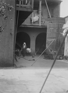 Courtyard with cistern and woman cleaning, New Orleans, between 1920 and 1926. Creator: Arnold Genthe.