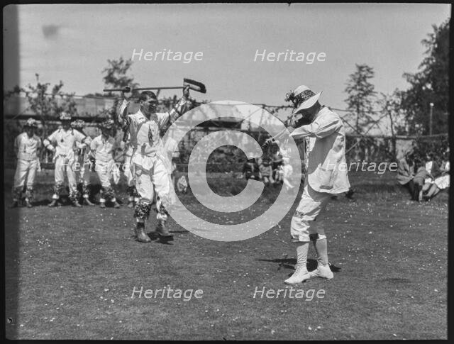 Bampton Morris troupe performing with a fiddler and someone holding a broom aloft, Oxon, 1920-30. Creator: George R Long.