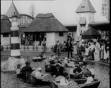 A Crowd of People Standing By a Boating Lake and Watch Other People in Paddle Boats, 1924. Creator: British Pathe Ltd.