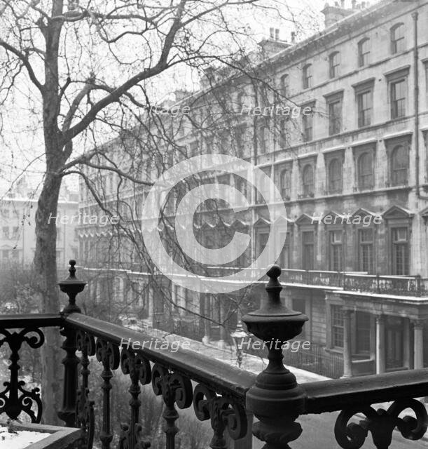 View of a lightly-snowy London square from a raised position behind a wrought-iron rail, 1947. Creator: John Gay.