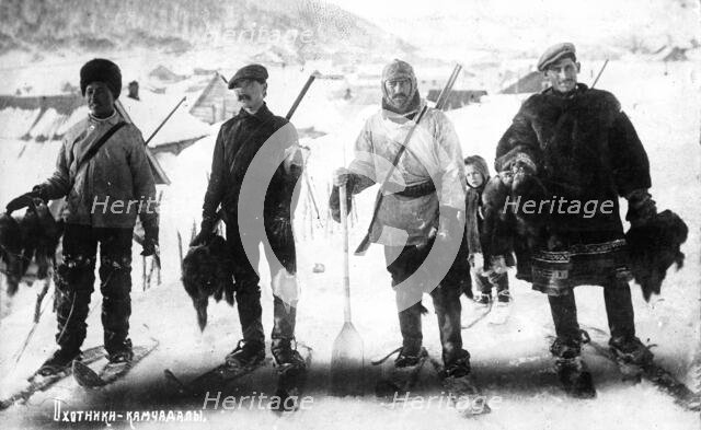 Kamchadal hunters against the backdrop of the city, with guns, furs, on skis, 1910-1929. Creator: Ivan Emelianovich Larin.