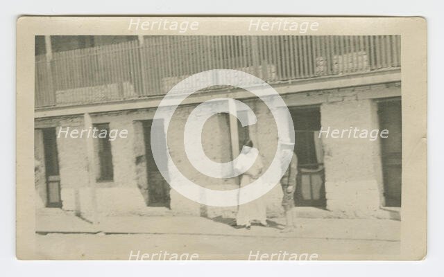 Photograph of a man and woman standing on a sidewalk, early 20th century. Creator: Unknown.